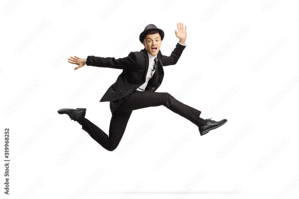 Young guy in a suit and top hat jumping high