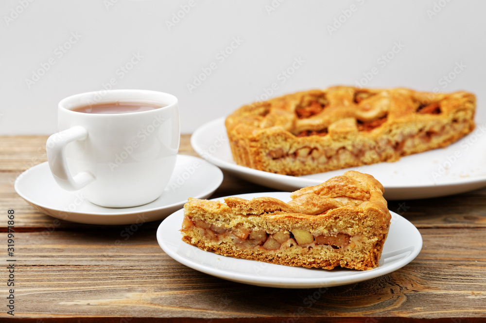 Homemade pie with apples and cinnamon and a cup of tea on wooden table. Shallow focus. Homemade pie with apples and cinnamon and a cup of tea on wooden table. Shallow focus.