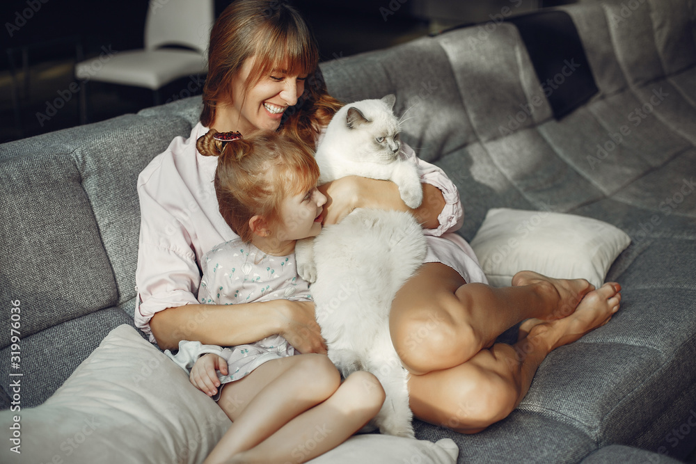Beautiful mother with little daughter. Family sitting in the room. Woman playing with a kitty Beautiful mother with little daughter. Family sitting in the room. Woman playing with a kitty