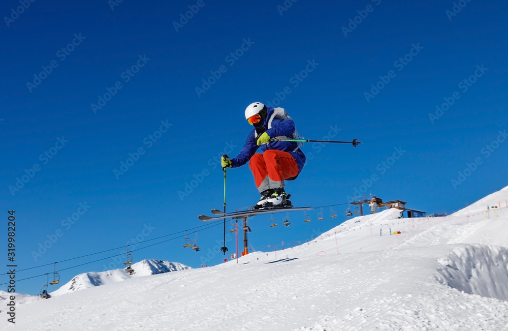 Skier jumps in snow park against the blue sky in Livigno ski resort, Italy