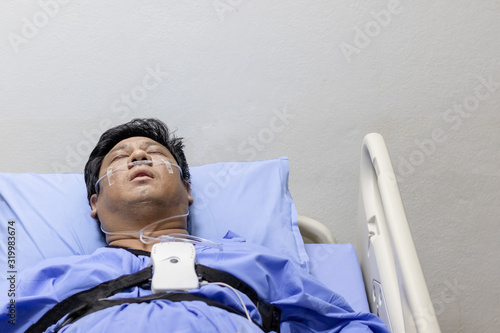 Asian Man Sleeping On A Patient Bed With Breathing Equipment in Hospital.