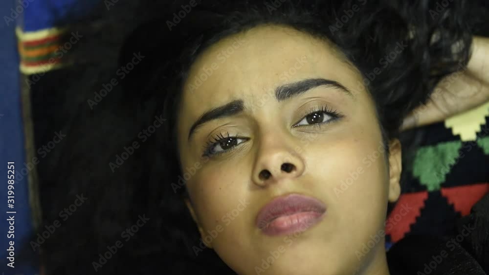 Beautiful smiling teen middle eastern girl wearing black top and relaxing in the bedroom. Portrait of a young middle eastern woman after naps daytime sleep on the bed at home with positive emotions fa Beautiful smiling teen middle eastern girl wearing black top and relaxing in the bedroom. Portrait of a young middle eastern woman after naps daytime sleep on the bed at home with positive emotions fa
