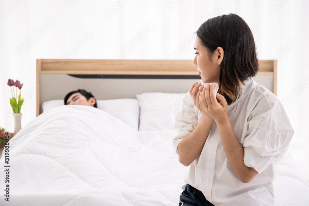 Worried woman sitting on the bed while her husband sleeping. Worried woman sitting on the bed while her husband sleeping.