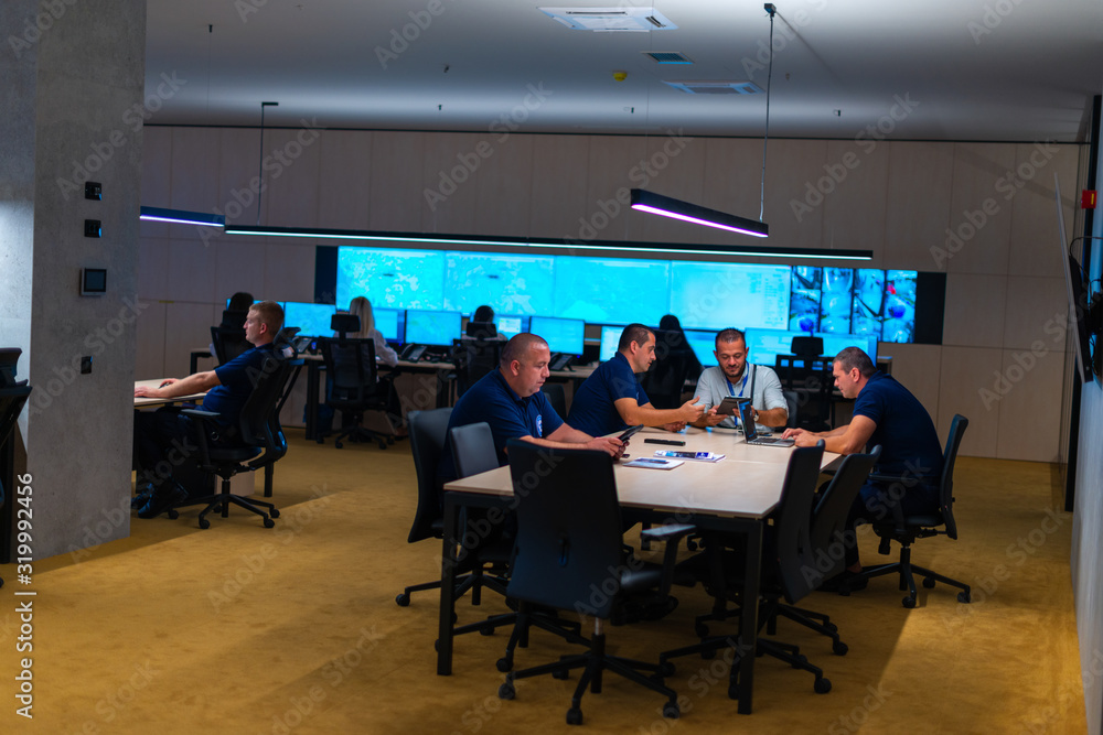 © qunica.com - Group of Security data center operators (administrators) working in a group at a CCTV monitoring room while looking at multiple monitors ( computer screens) © qunica.com - Group of Security data center operators (administrators) working in a group at a CCTV monitoring room while looking at multiple monitors ( computer screens)