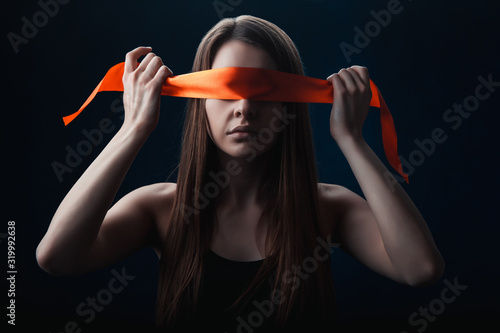 the girl blindfolded herself, with red tape, a game on a black background photo