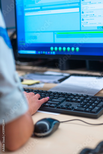 Close up photo of a security data center operator (agent )typing on her keyboard while monitoring the cctv system.