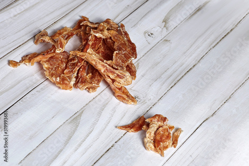 Dehydrated homemade chicken or turkey pet chips on white wooden background with big empty copy space for any text. Dog and cat chewy jerky and treats. Indoors, close up.