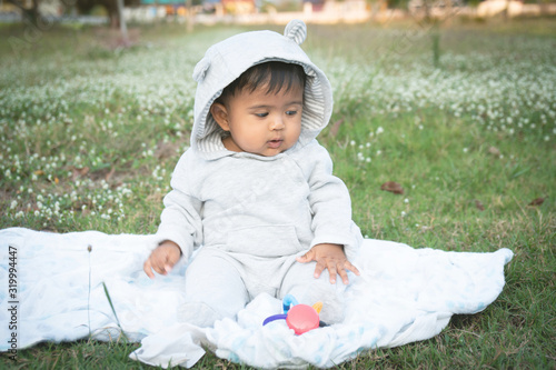 Cute little asina baby sitting at white flower garden