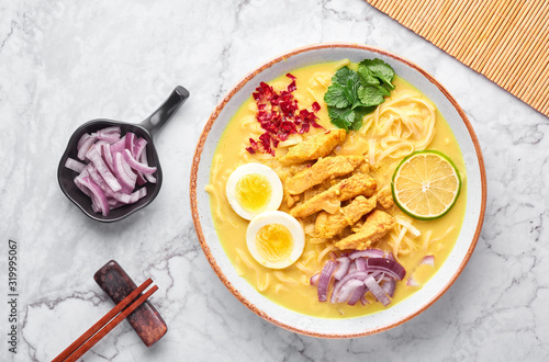 Ohn No Khao Swe on white marble background. Oh No Khao Suey is Coconut Milk Noodle Soup of myanmar cuisine with chicken meat and eggs. Burmese food. Top view photo