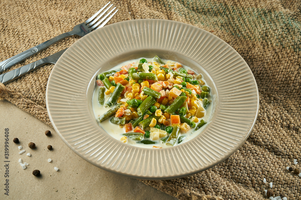 Healthy food - steamed vegetables in a creamy sauce in a ceramic bowl on rustic background. Tasty lunch. Close up