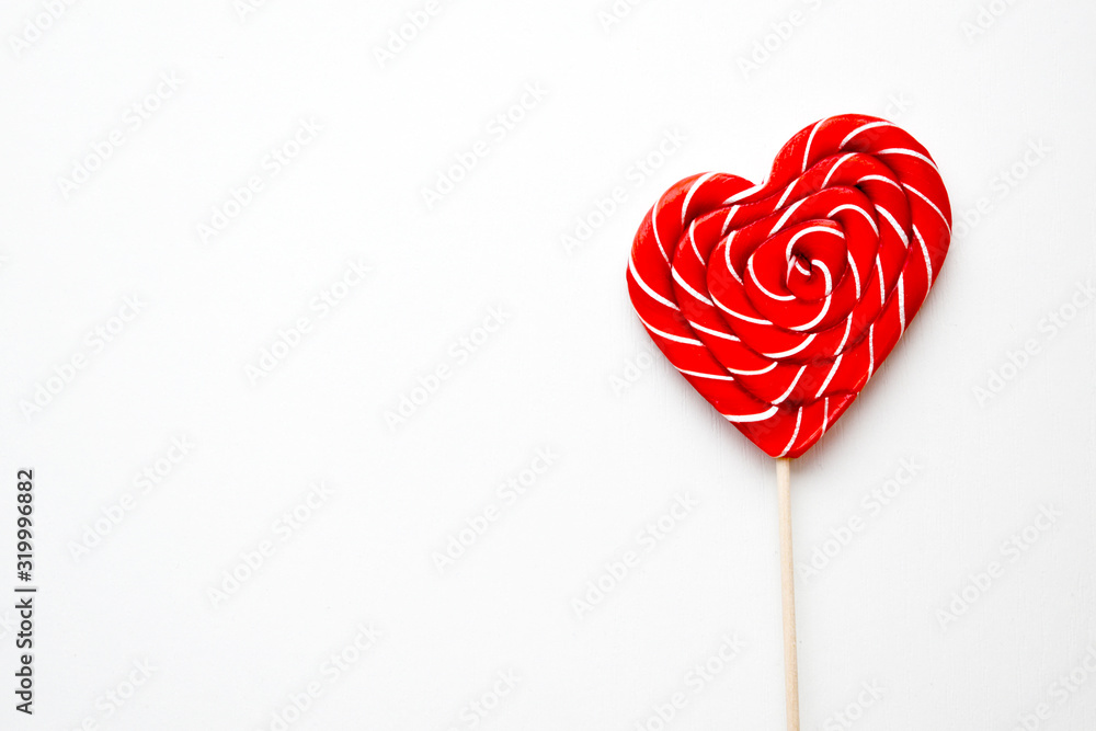 red lollipop in shape of heart on white background