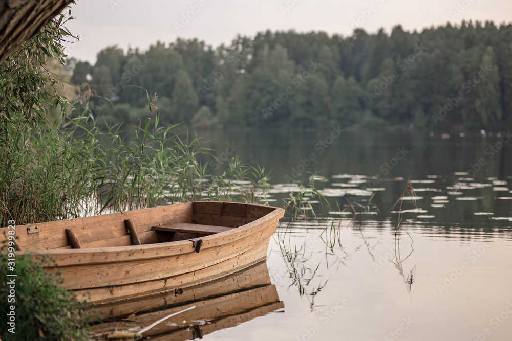 Sunset over the river in autumn. Romantic view of wooden fishing boat in the pond and forest. Sunset over the river in autumn. Romantic view of wooden fishing boat in the pond and forest.