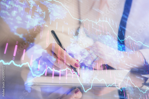 Double exposure of hands making notes with forex chart huds. Stock market concept.