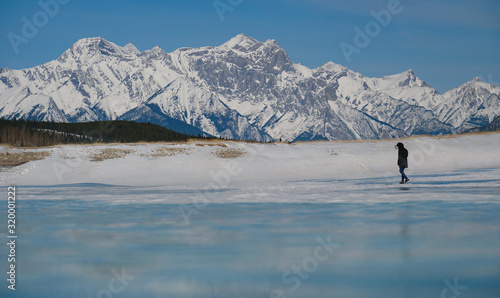 LOW ANGLE: Unrecognizable tourist walks across a frozen lake in Rocky Mountains
