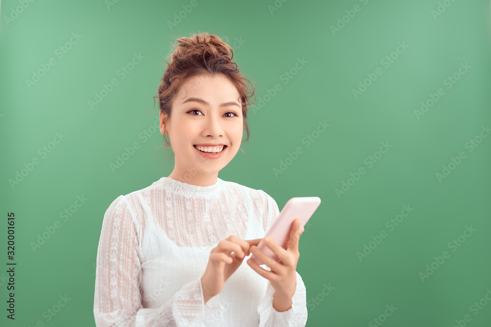 Attractive beautiful Asian woman using mobile phone while smiling isolated over green background. Attractive beautiful Asian woman using mobile phone while smiling isolated over green background.