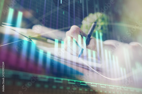 Financial forex graph displayed on hands taking notes background. Concept of research. Multi exposure