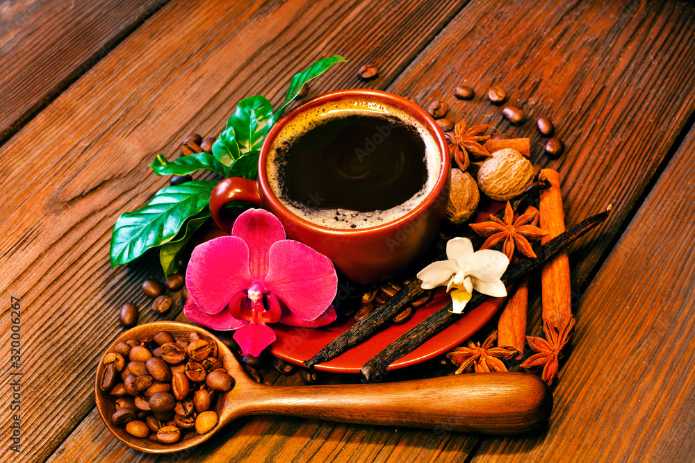 Hot coffee cup and coffee beans with spices and orchid flowers on a wooden table. Hot coffee cup and coffee beans with spices and orchid flowers on a wooden table.