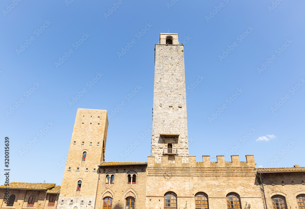 Fototapeta premium Rognosa tower and the Palace of the Podesta in the historic centre of San Gimignano (Piazza Duomo), province of Siena, Tuscany, Italy