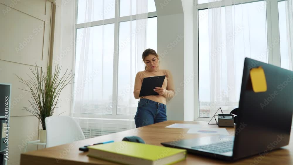 Pensive girl with clipboard working in modern office Pensive girl with clipboard working in modern office