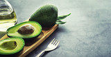 Avocado cooking recipes. Ripe green avocado on a wooden cutting board for serving.