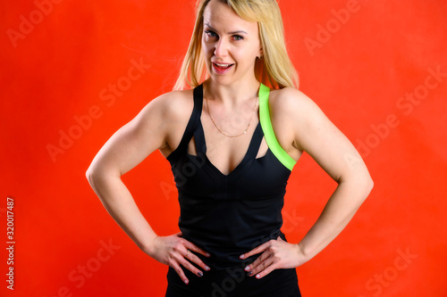 Wallpaper Mural The concept of fashionable fitness. Photo of a beautiful pretty slim woman blonde sportswoman in a tracksuit on a red background. Standing in different poses with emotions and a smile. Torontodigital.ca