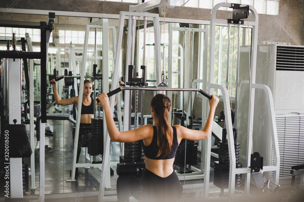 Beautiful athlete exercising with a lat pulldown machine to play the arms and shoulder muscles in the gym. Beautiful athlete exercising with a lat pulldown machine to play the arms and shoulder muscles in the gym.