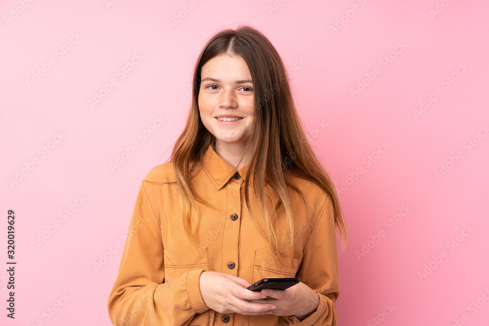 Ukrainian teenager girl over isolated pink background sending a message with the mobile Ukrainian teenager girl over isolated pink background sending a message with the mobile