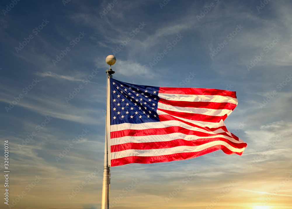 Obraz premium An American flag blowing in the wind over a blue sky
