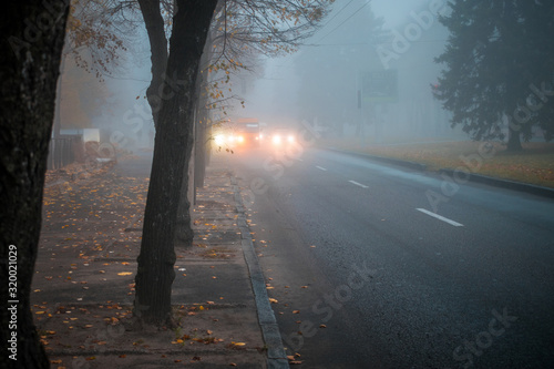 Wallpaper Mural Heavy fog on the road in the early morning. City street with cars in the distance is in poor visibility. The bright light of the headlights of the car. Blurry fog effect. Torontodigital.ca