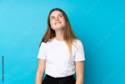 Ukrainian teenager girl over isolated blue background laughing and looking up © luismolinero