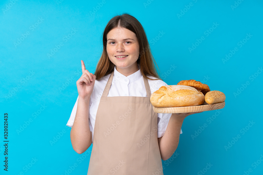 Ukrainian teenager chef uniform. Female baker holding a table with several breads pointing up a great idea Ukrainian teenager chef uniform. Female baker holding a table with several breads pointing up a great idea