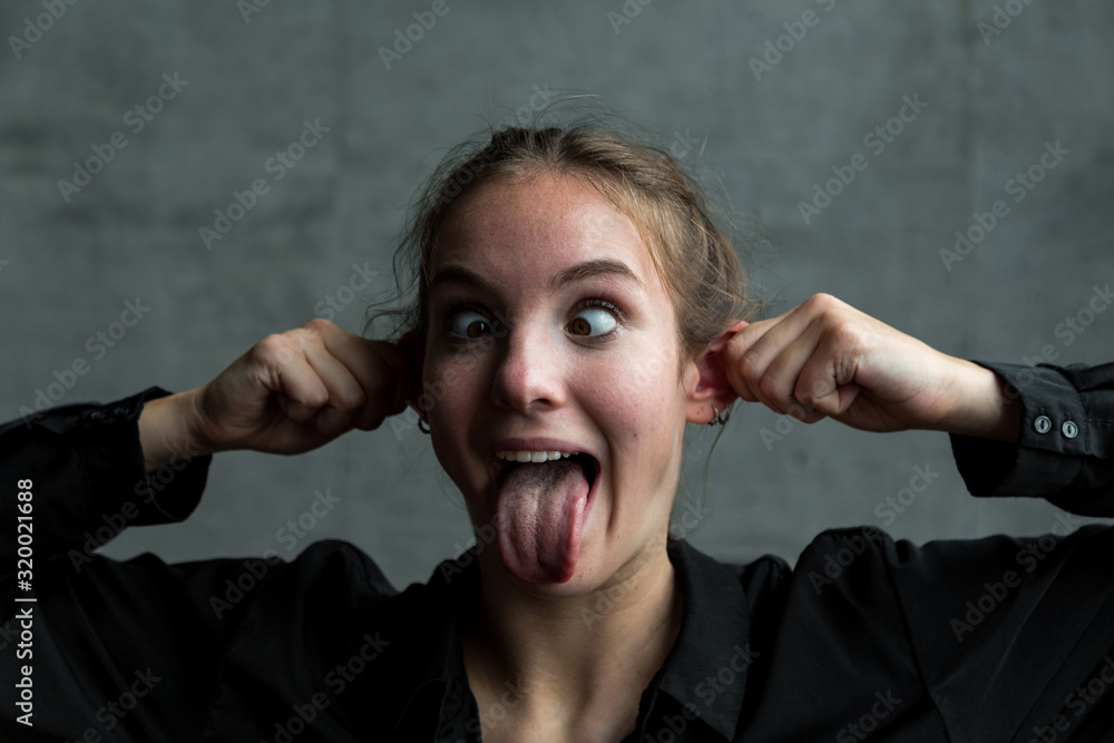 Young Woman Pulling Ears with Eyes Crossed and Tongue Sticking Out Stock Photo Adobe Stock