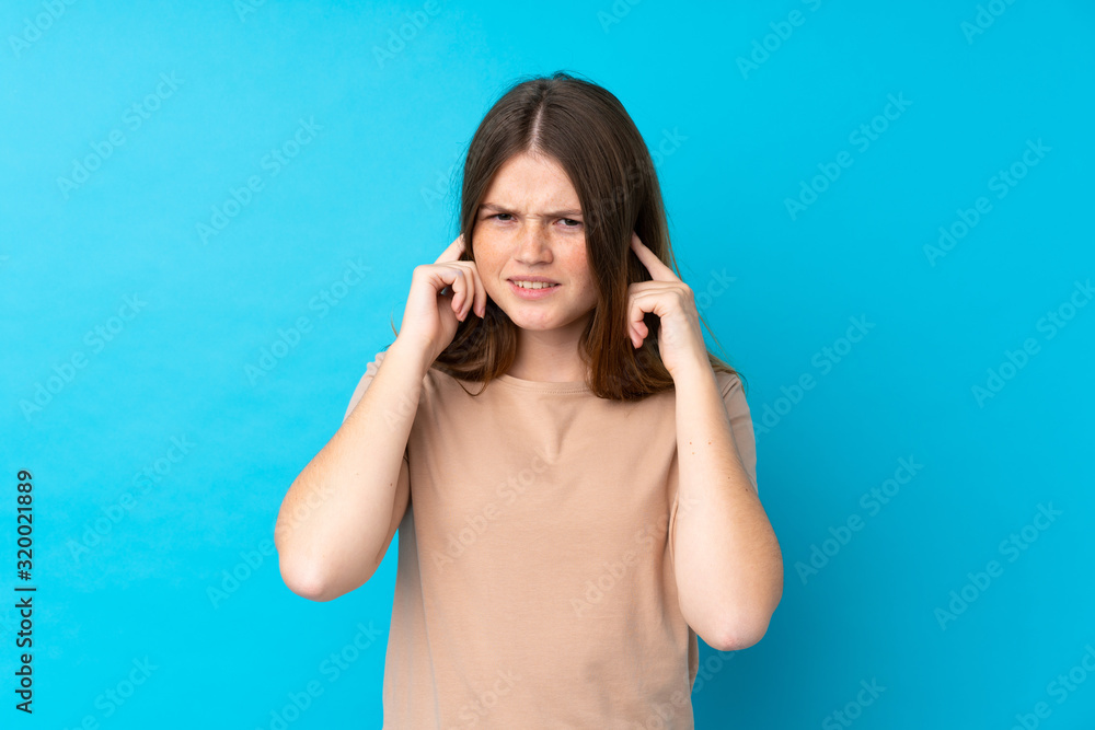 Ukrainian teenager girl over isolated blue background frustrated and covering ears Ukrainian teenager girl over isolated blue background frustrated and covering ears