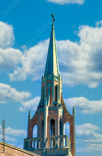 Billede på lærred An old church steeple with bell tower against a blue sky