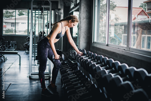 Beautiful female athletes are exercising in the gym. By lifting the dumbbell. The gym has a full range of exercise equipment.
