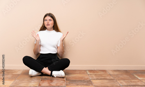 Ukrainian teenager girl sitting on the floor frustrated by a bad situation
