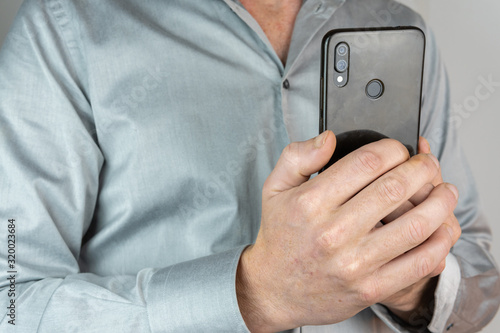 man with blue shirt with mobile phone in hands