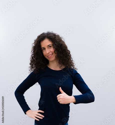 young pretty black hair woman feeling proud, carefree, confident and happy, smiling positively with thumbs up