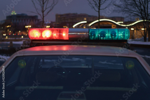 Police use at night. City street in winter. Harassment of the offender. To protect and serve.  American car, 80s. Offense against the law. Defocused cityscape as background.