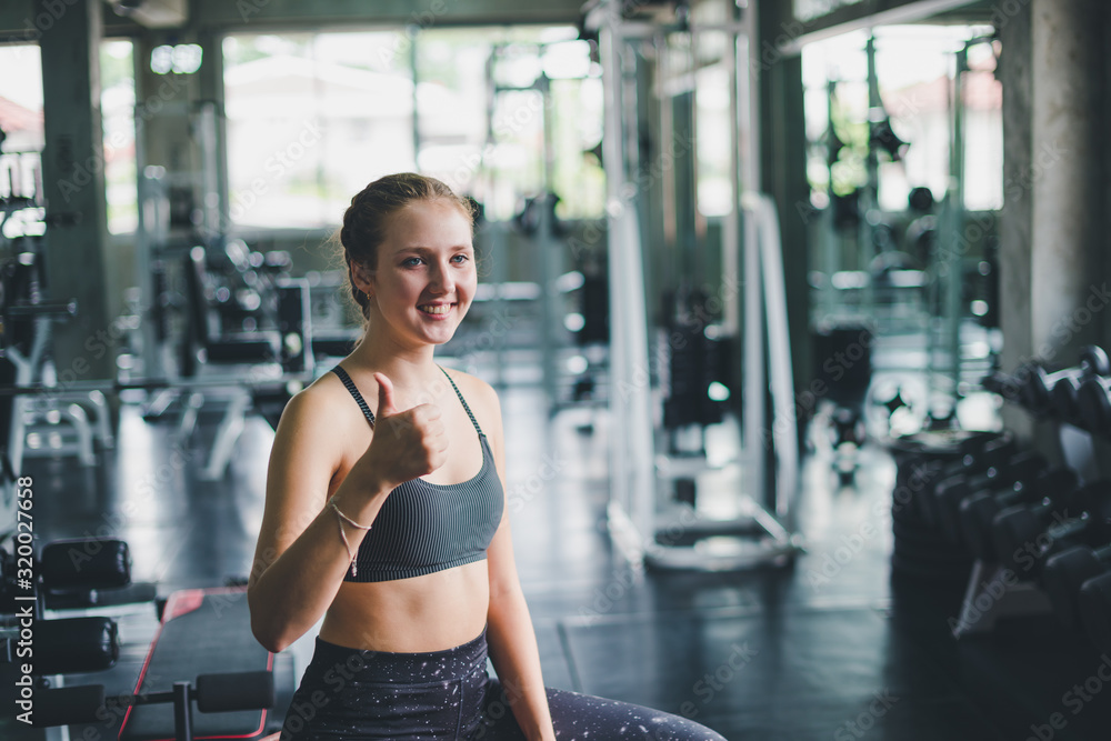 Fototapeta premium A beautiful young woman wearing a relaxing sports shirt with a rubber ball, yoga or exercise ball.