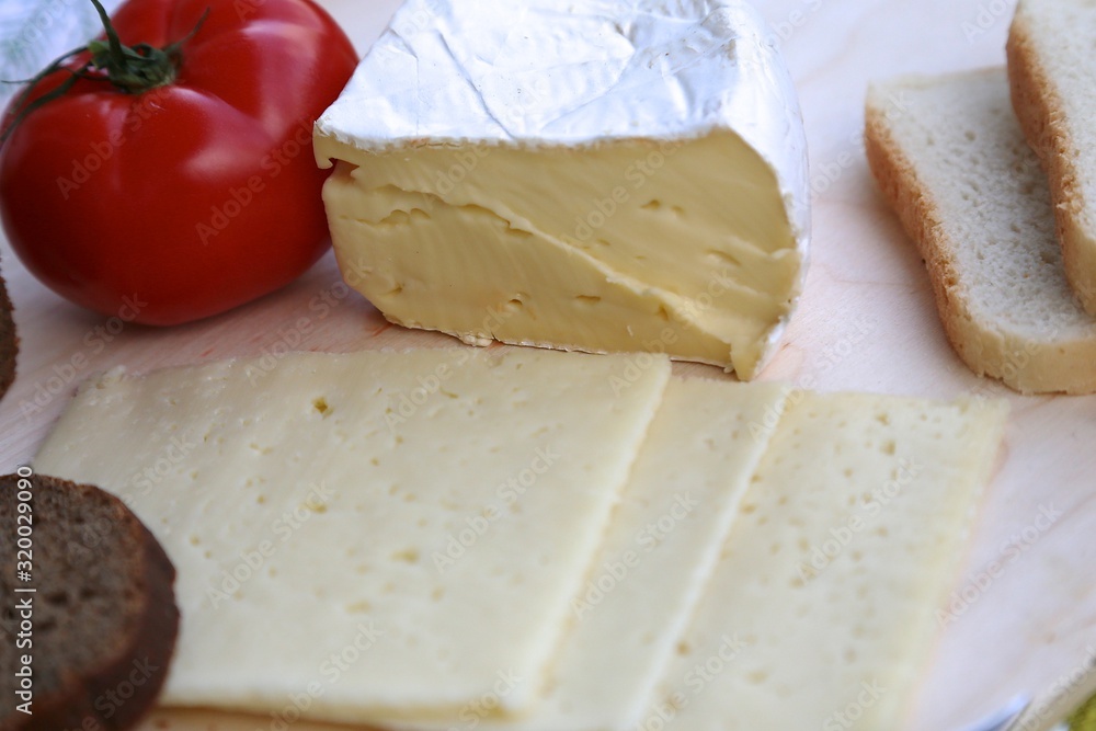 Homemade cheese on the board cut to pieces.