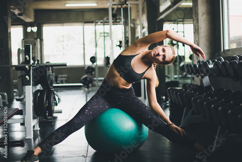 A beautiful woman wearing a sports shirt, stretching and relaxing with a rubber ball, yoga or exercise ball.