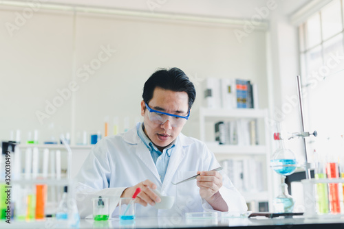 Asian scientists are preparing chemicals for testing and analysis in the laboratory. Scientists clear glasses and white shirts. Science and Chemistry Concept