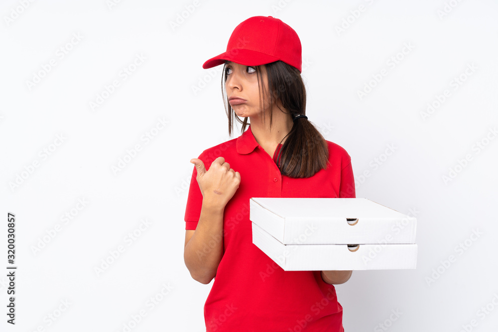 Young Pizza delivery girl over isolated white background unhappy and pointing to the side Young Pizza delivery girl over isolated white background unhappy and pointing to the side
