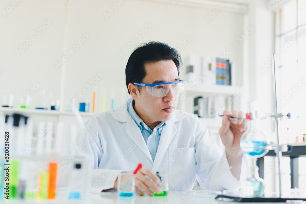 Asian scientists are preparing chemicals for testing and analysis in the laboratory. Scientists clear glasses and white shirts. Science and Chemistry Concept Asian scientists are preparing chemicals for testing and analysis in the laboratory. Scientists clear glasses and white shirts. Science and Chemistry Concept