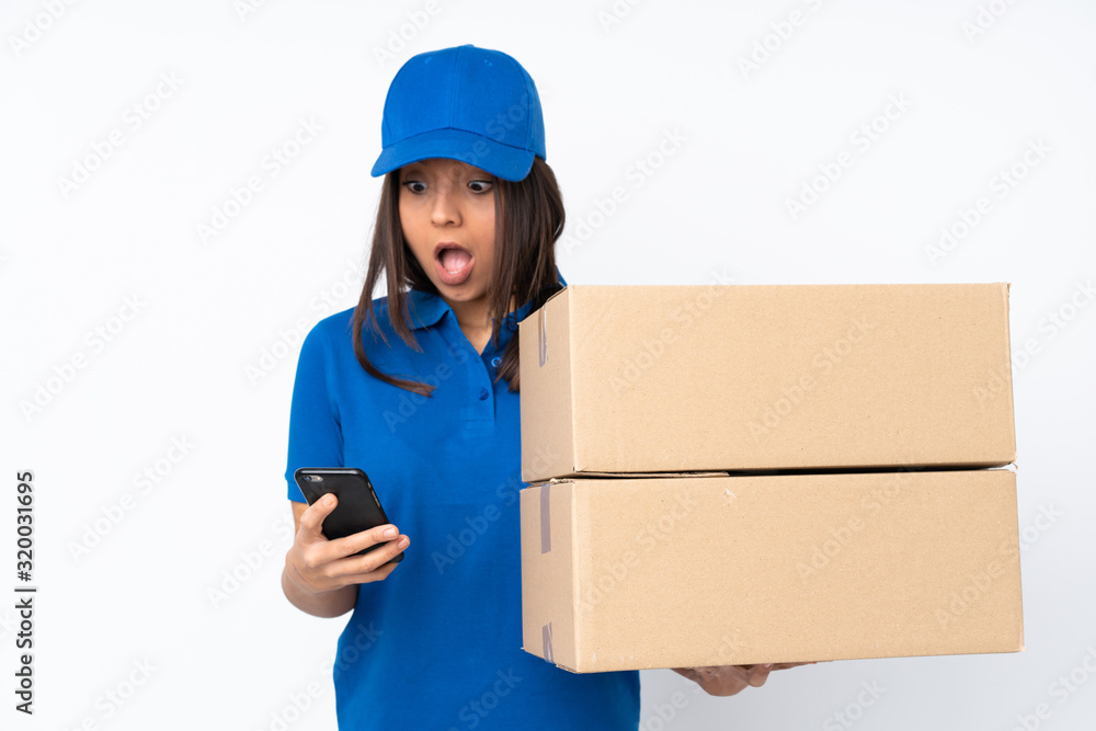 Young delivery brunette girl over isolated white background surprised and sending a message Young delivery brunette girl over isolated white background surprised and sending a message