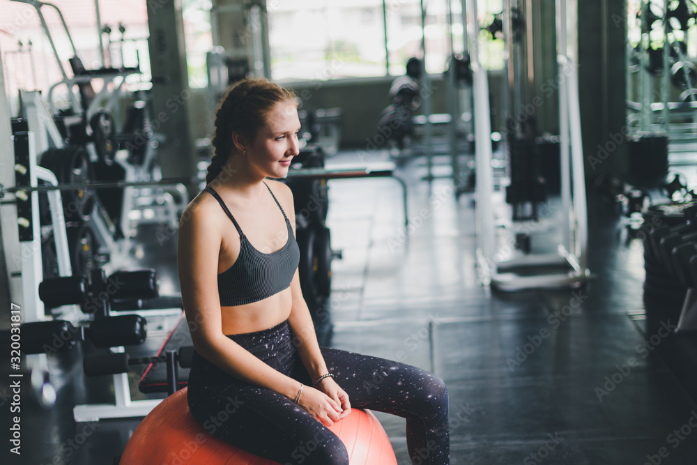 A beautiful young woman wearing a relaxing sports shirt with a rubber ball, yoga or exercise ball. A beautiful young woman wearing a relaxing sports shirt with a rubber ball, yoga or exercise ball.