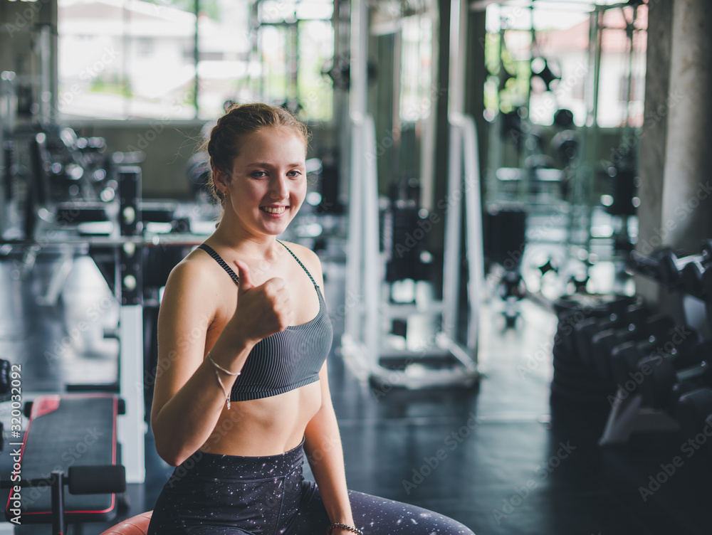 Fototapeta premium A beautiful young woman wearing a relaxing sports shirt with a rubber ball, yoga or exercise ball.