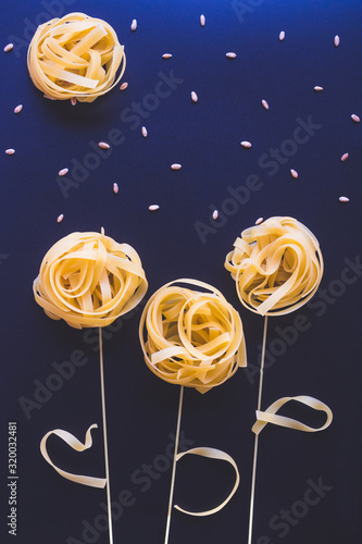 uncooced italian pasta fettuccine. Pasta flowers on a star sky classic blue background photo