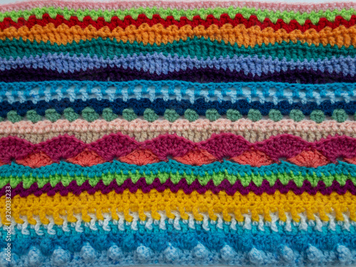 Multicolor wool crochet stitches blanket textile in bright colors background texture